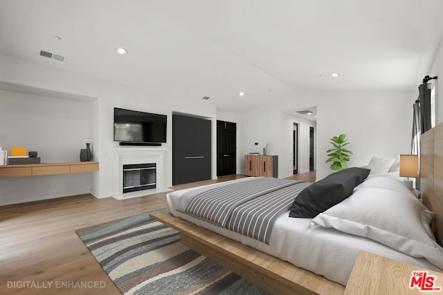 bedroom featuring lofted ceiling and light hardwood / wood-style flooring