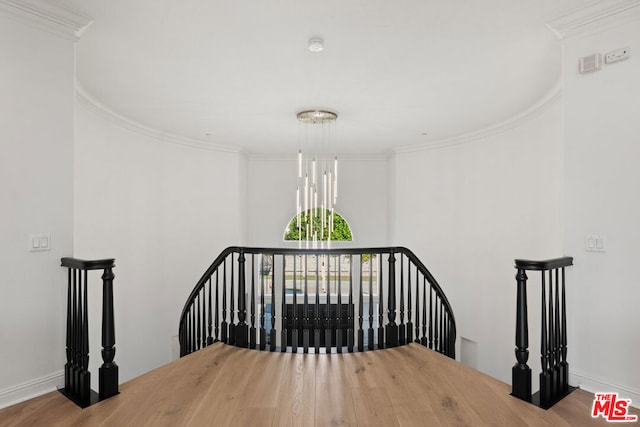 stairs featuring crown molding, a chandelier, and hardwood / wood-style flooring