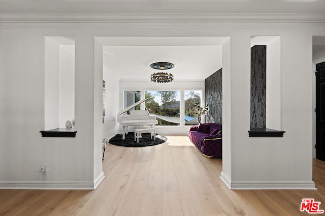 hallway with light wood-type flooring and crown molding