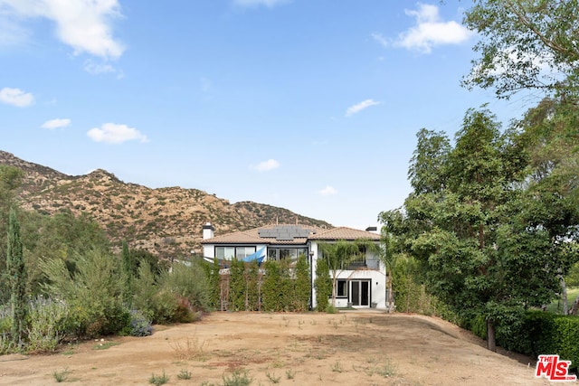 rear view of property featuring a mountain view and solar panels