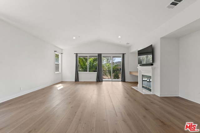 unfurnished living room with light wood-type flooring and vaulted ceiling