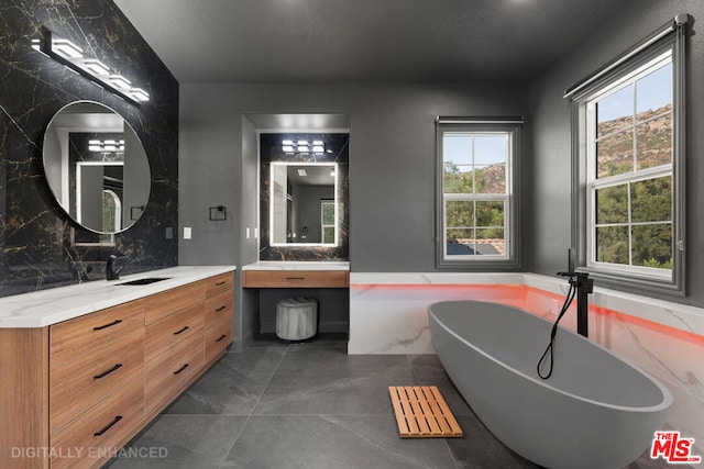 bathroom featuring tile patterned floors, vanity, a tub, and a healthy amount of sunlight