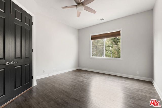 empty room featuring ceiling fan and dark wood-type flooring