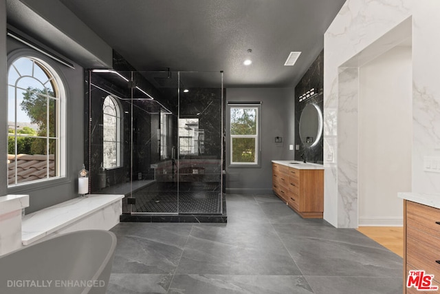 bathroom featuring plus walk in shower, vanity, and a textured ceiling