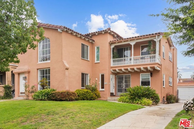 mediterranean / spanish house featuring a garage, a balcony, and a front lawn