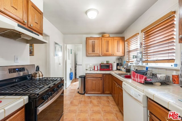 kitchen with dishwasher, tile countertops, and gas stove