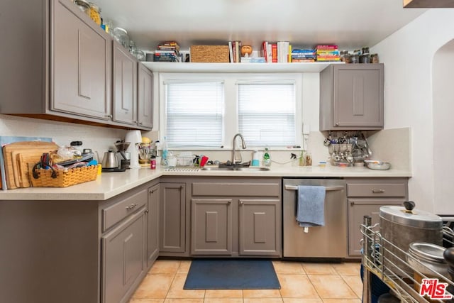 kitchen featuring light tile patterned flooring, sink, stainless steel dishwasher, gray cabinets, and decorative backsplash