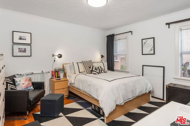 bedroom featuring ornamental molding and light wood-type flooring