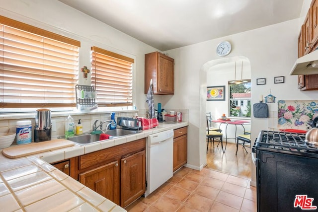 kitchen featuring white dishwasher, black gas stove, tile counters, and a healthy amount of sunlight