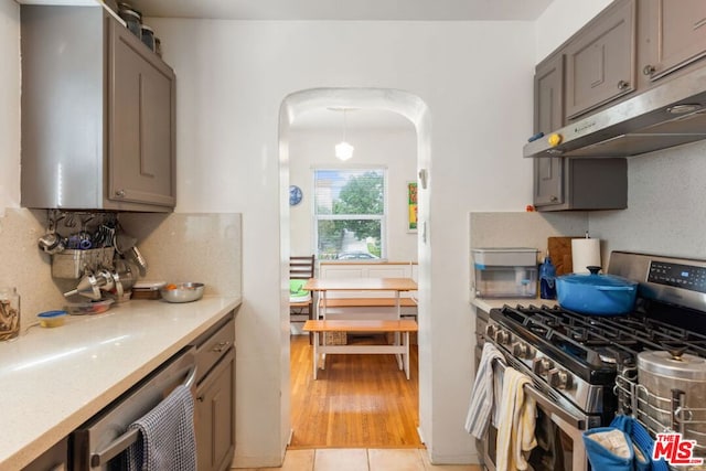 kitchen featuring light wood-type flooring, decorative backsplash, and stainless steel appliances