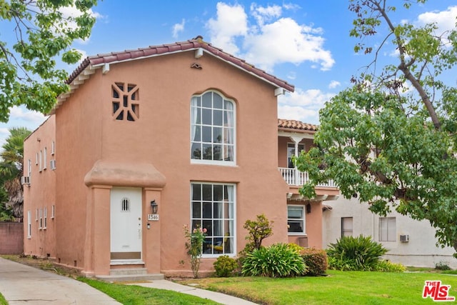 mediterranean / spanish-style house with a balcony and a front lawn