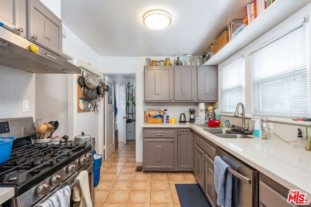 kitchen featuring light tile patterned flooring, sink, gray cabinetry, extractor fan, and stainless steel appliances