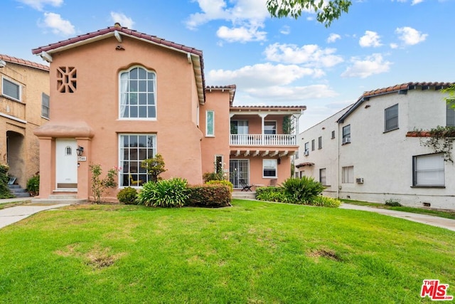 mediterranean / spanish home featuring a balcony and a front lawn