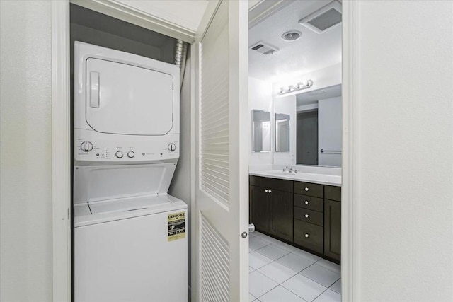 laundry room with light tile patterned floors, stacked washer / dryer, and sink