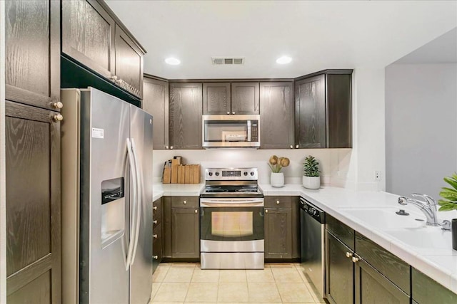 kitchen with dark brown cabinets, sink, stainless steel appliances, and light tile patterned flooring