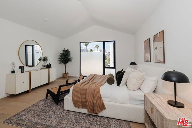 bedroom featuring lofted ceiling and light wood-type flooring