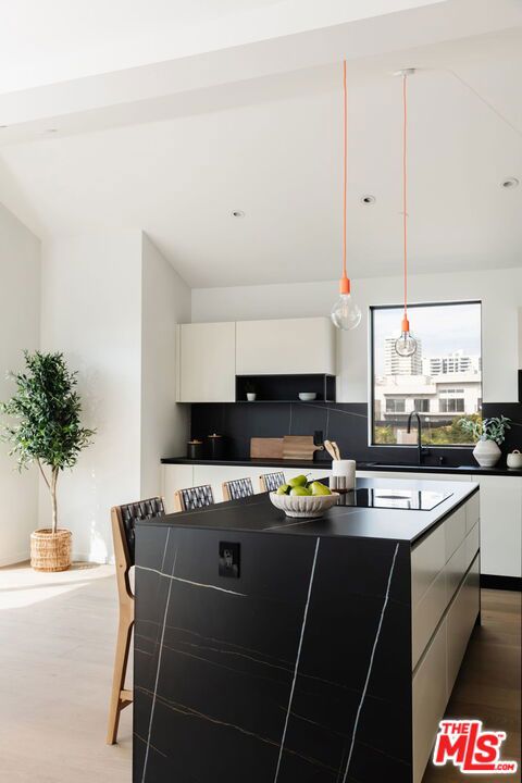 kitchen with white cabinets, decorative backsplash, a center island, and wood-type flooring