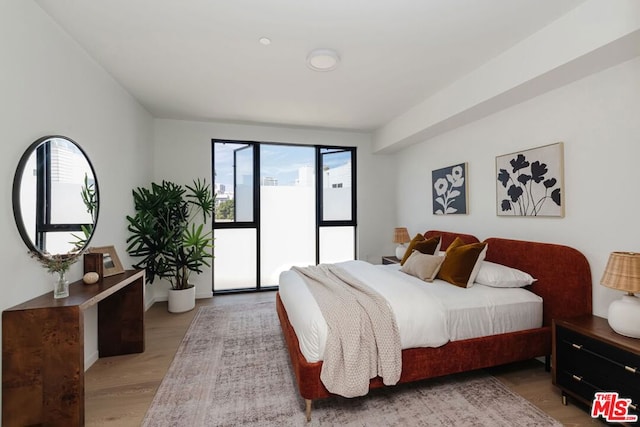 bedroom featuring access to outside, multiple windows, and light hardwood / wood-style flooring