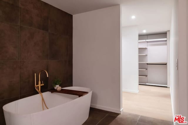 bathroom featuring tile patterned floors, tile walls, and a bathing tub