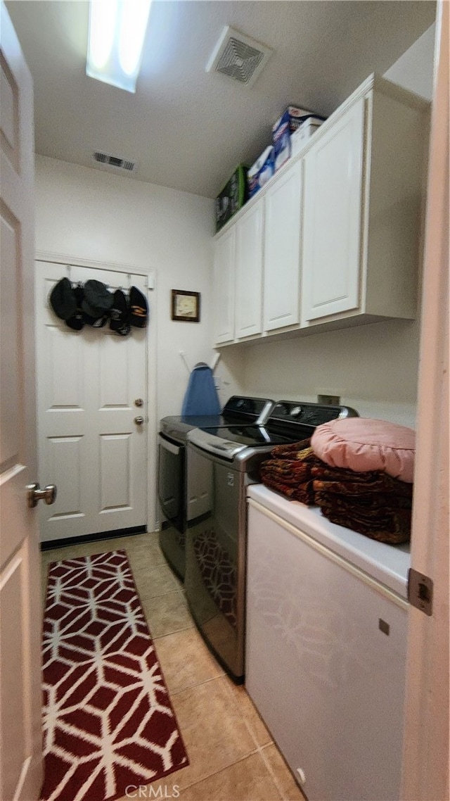 washroom featuring light tile patterned floors, separate washer and dryer, and cabinets