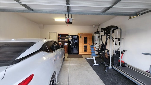 garage featuring a garage door opener, water heater, and black refrigerator