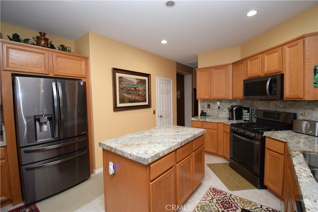 kitchen featuring light stone countertops, a center island, appliances with stainless steel finishes, and tasteful backsplash