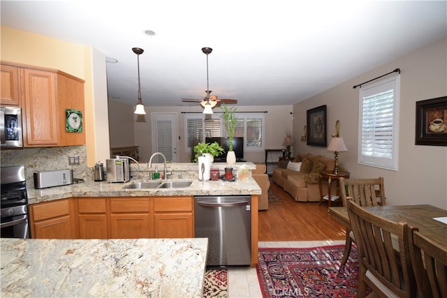 kitchen with appliances with stainless steel finishes, kitchen peninsula, sink, and ceiling fan