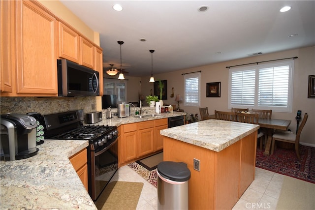 kitchen featuring sink, black appliances, a center island, and light stone counters