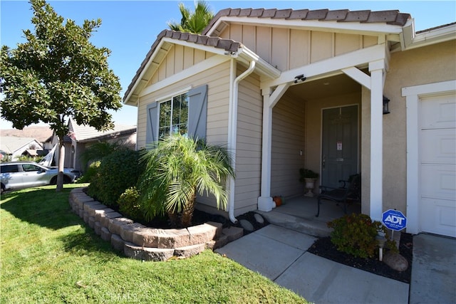 view of exterior entry featuring a garage and a lawn