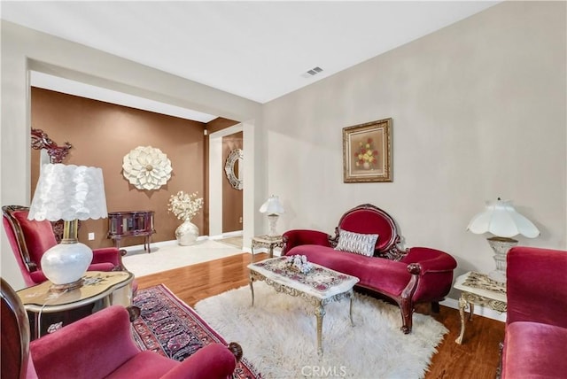 living room with baseboards, visible vents, and wood finished floors