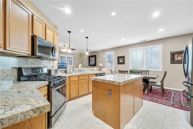 kitchen featuring tasteful backsplash, hanging light fixtures, appliances with stainless steel finishes, light tile patterned flooring, and a kitchen island