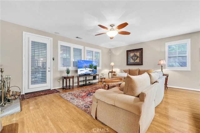 living area with light wood finished floors, plenty of natural light, baseboards, and ceiling fan