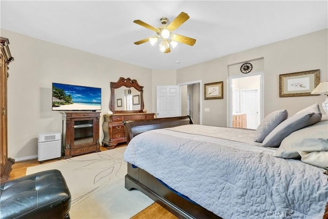 bedroom featuring a ceiling fan, connected bathroom, light wood-style flooring, and baseboards