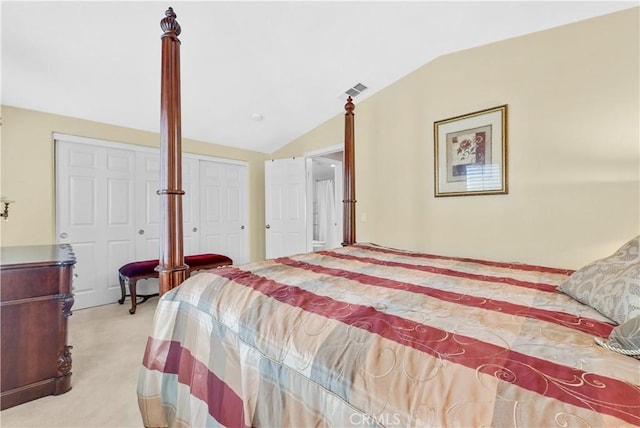 bedroom with lofted ceiling, two closets, visible vents, and light colored carpet