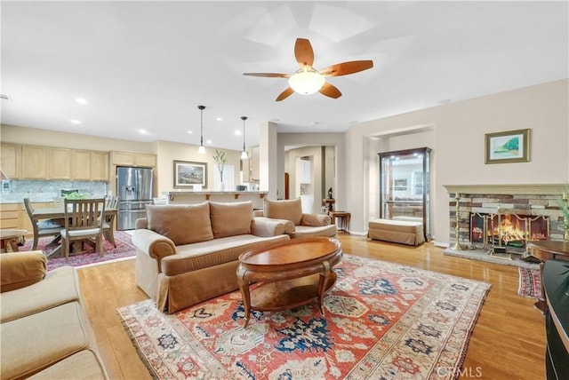 living area featuring a ceiling fan, light wood-type flooring, a fireplace, and recessed lighting