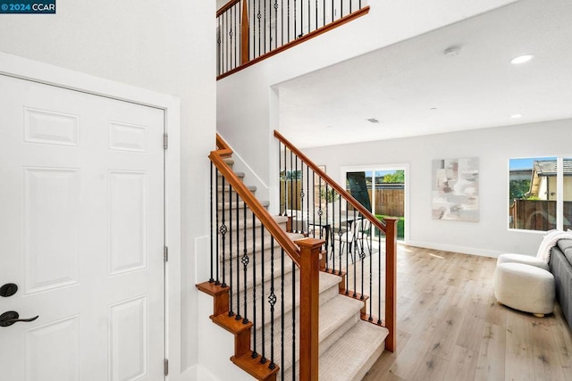 staircase featuring a healthy amount of sunlight and hardwood / wood-style flooring