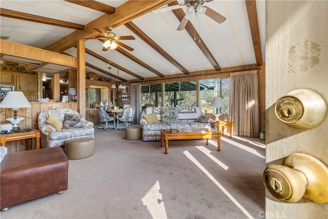 carpeted living room featuring ceiling fan with notable chandelier and vaulted ceiling with beams