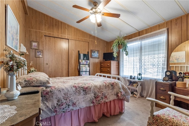 bedroom with carpet floors, wood walls, vaulted ceiling, and ceiling fan