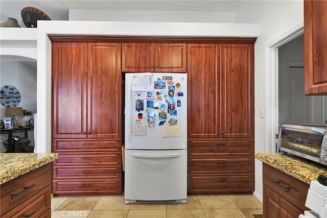 kitchen with white refrigerator, light stone countertops, and light tile patterned floors