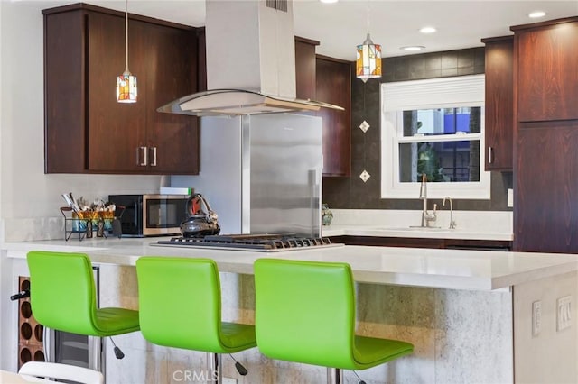 kitchen with ventilation hood, a breakfast bar, pendant lighting, and stainless steel appliances