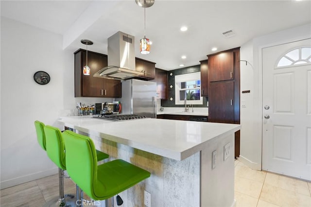 kitchen featuring sink, hanging light fixtures, a kitchen bar, island exhaust hood, and stainless steel appliances