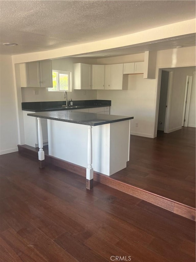 kitchen with dark hardwood / wood-style flooring, white cabinetry, and sink