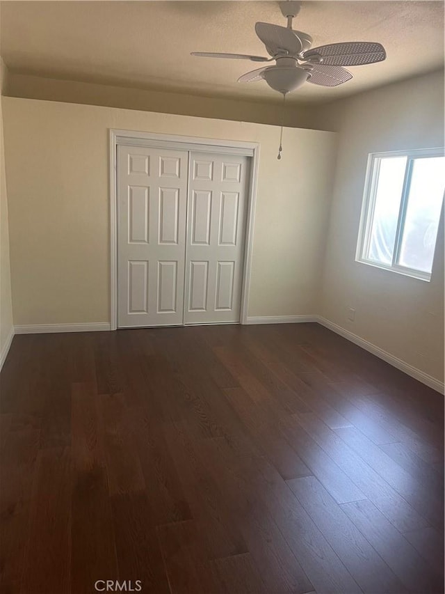 unfurnished bedroom with ceiling fan, dark hardwood / wood-style flooring, and a closet