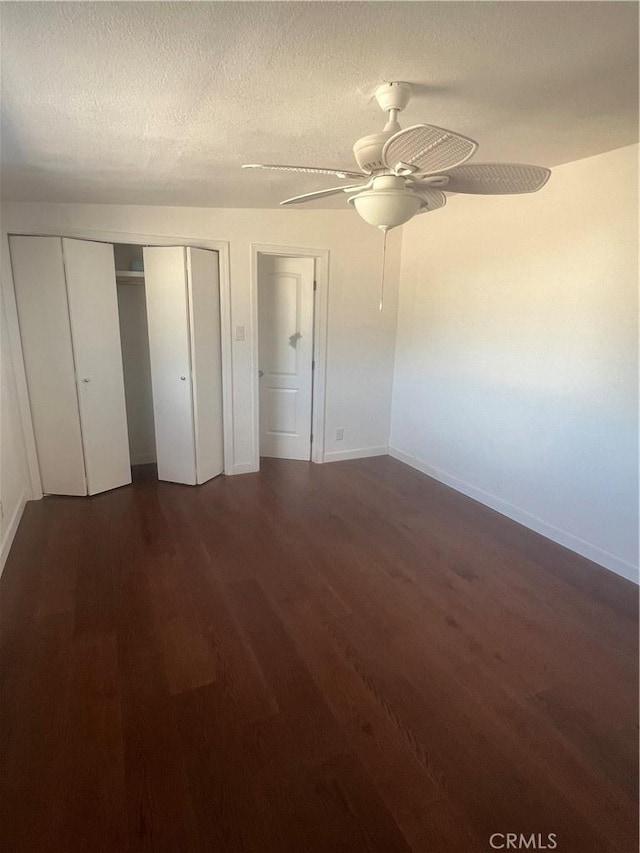 unfurnished bedroom with ceiling fan, dark hardwood / wood-style flooring, and a textured ceiling