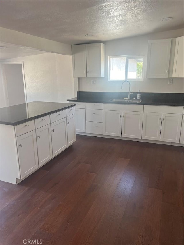 kitchen featuring white cabinetry, dark hardwood / wood-style flooring, a textured ceiling, and sink