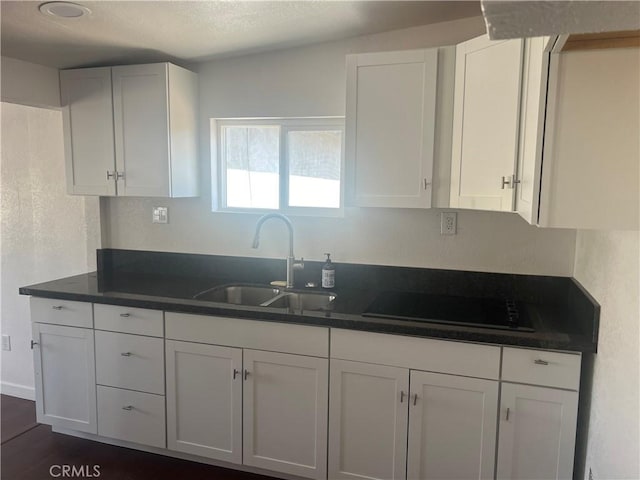 kitchen with cooktop, dark hardwood / wood-style floors, white cabinetry, and sink