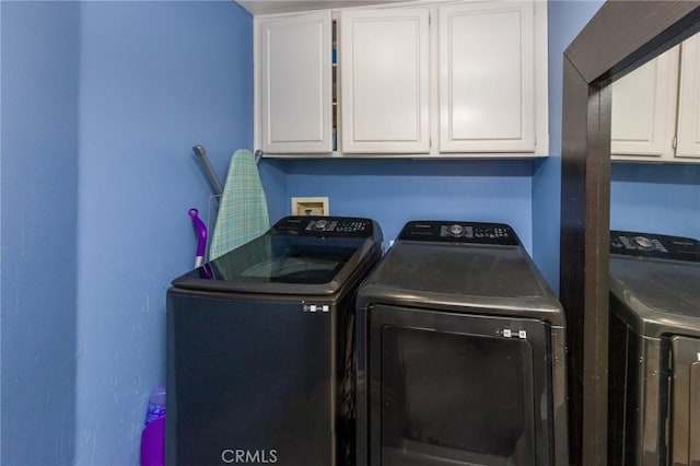 clothes washing area featuring washer and dryer and cabinets