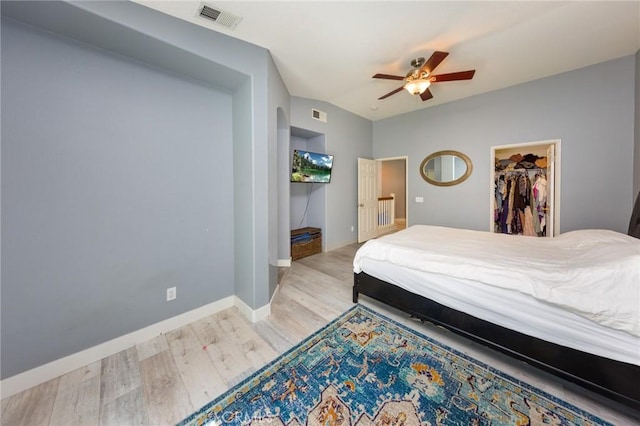 bedroom with ceiling fan, light hardwood / wood-style floors, a spacious closet, and a closet