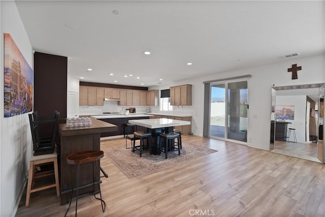 kitchen with sink, a kitchen breakfast bar, a kitchen island, and light hardwood / wood-style flooring