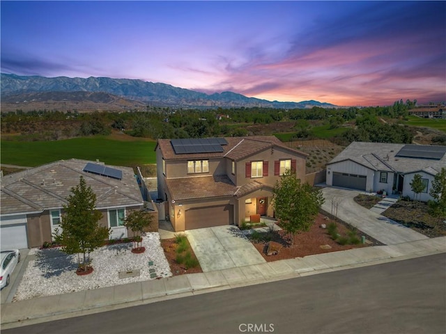 view of front of house with a garage, a mountain view, and solar panels